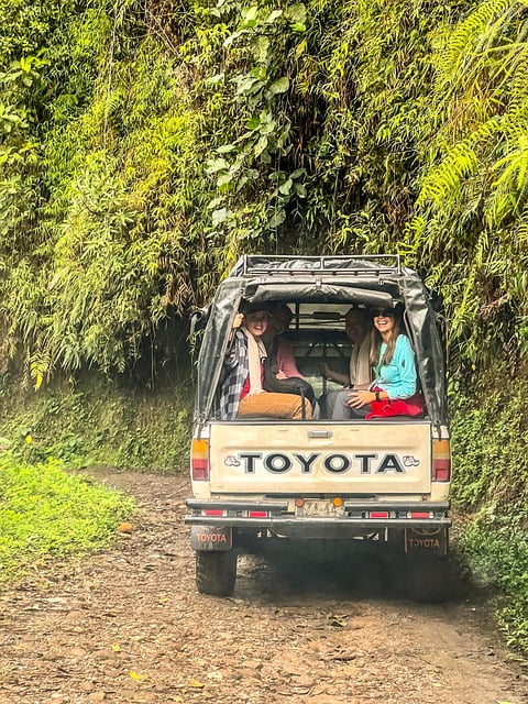 A group of tourists sitting in the back of a small Toyota off-road vehicle, surrounded by tropical vegetation during a Colombian adventure tour.