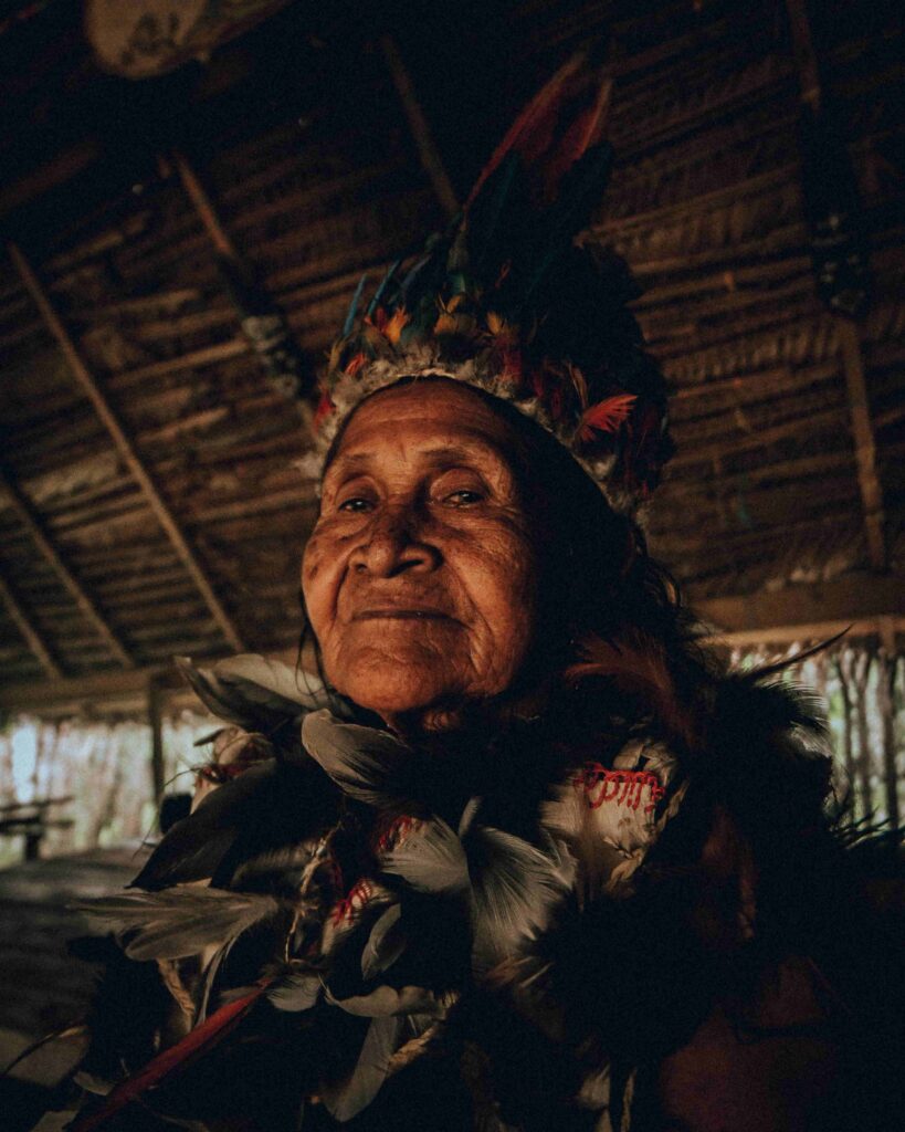 Indigenous woman wearing traditional clothing inside a wooden house in Puerto Nariño, Amazon Region, Colombia