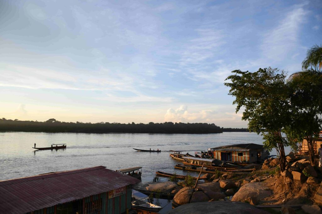 River view of the Inirida River with small boats and houses along the riverbank surrounded by vegetation in Colombia
