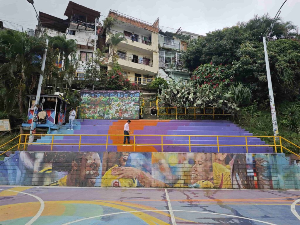 Colorful sports court surrounded by hillside homes in Medellín, showing the vibrant everyday life of the comunas.