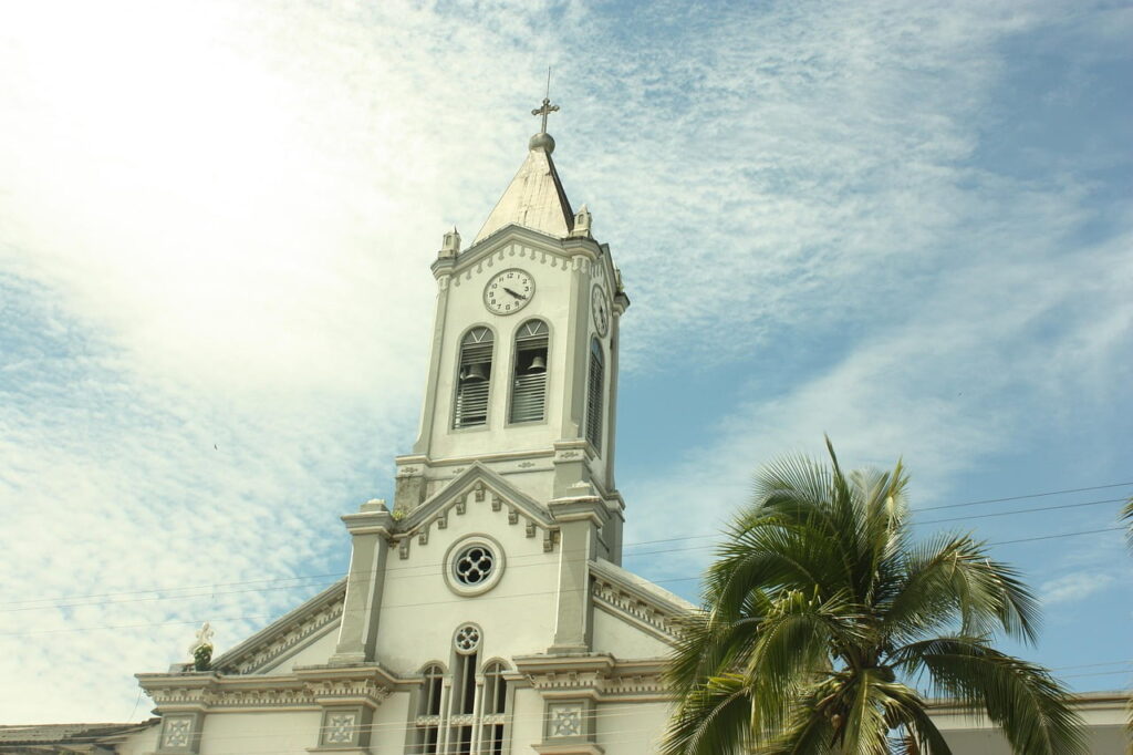 White traditional church in Mocoa with a wax palm tree and clear blue sky in Putumayo, Colombia