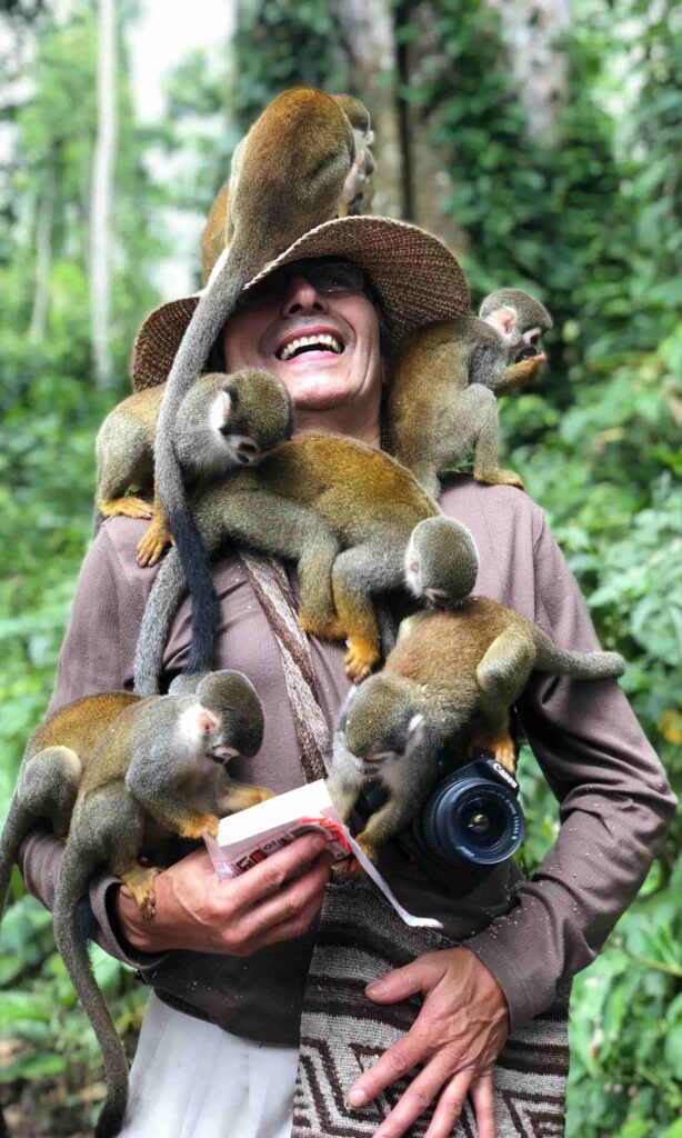 Tourist surrounded by monkeys in the rainforest on Monkey Island in Leticia, Colombia