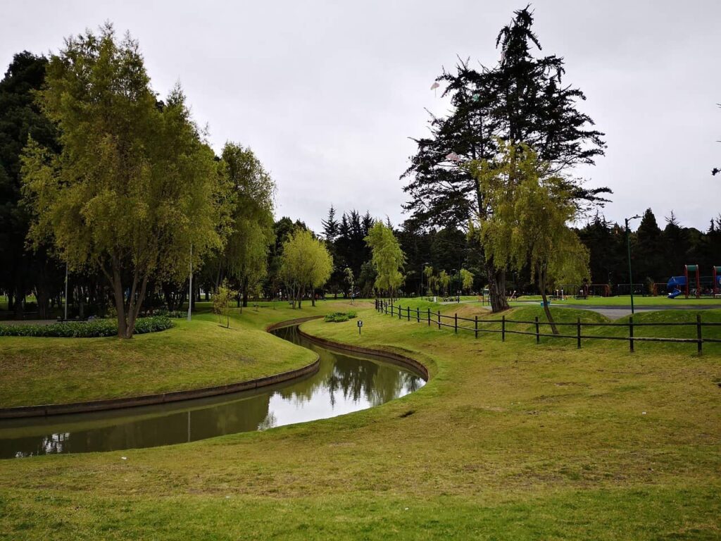 Green landscape of Simon Bolivar Park in Bogotá with trees and a small lake running through the middle
