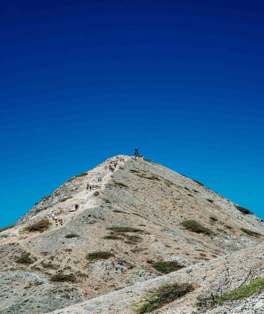 People climbing the rock at Cabo de la Vela with desert landscape in La Guajira, Colombia.