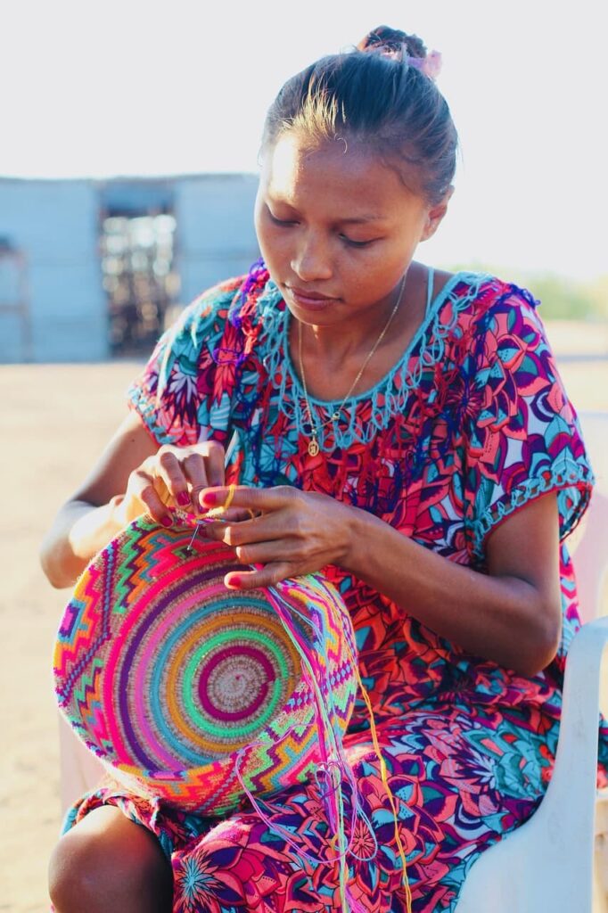 Indigenous Wayuu girl weaving a traditional handmade bag in La Guajira, Colombia.