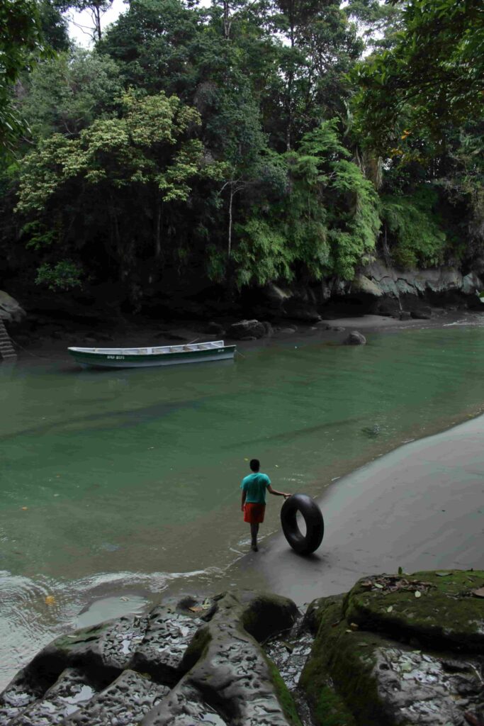 bahia-malaga-pacific-coast-jungle-colombia A small boat in a narrow sea passage in Bahia Malaga, with a man on the shore and lush jungle.
