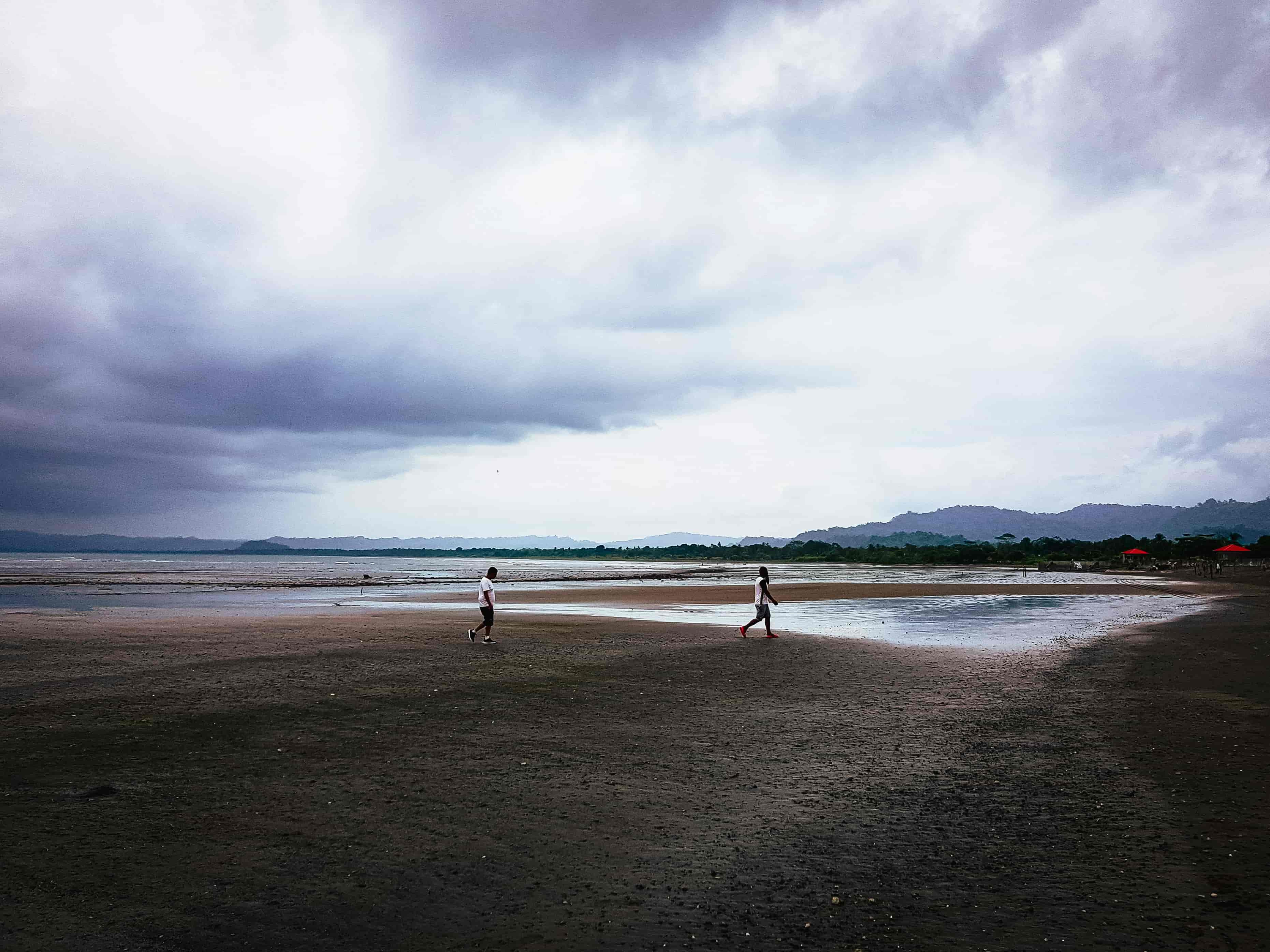 Two men walking on a wide beach in Choco, representing the vast Colombian Pacific coast.